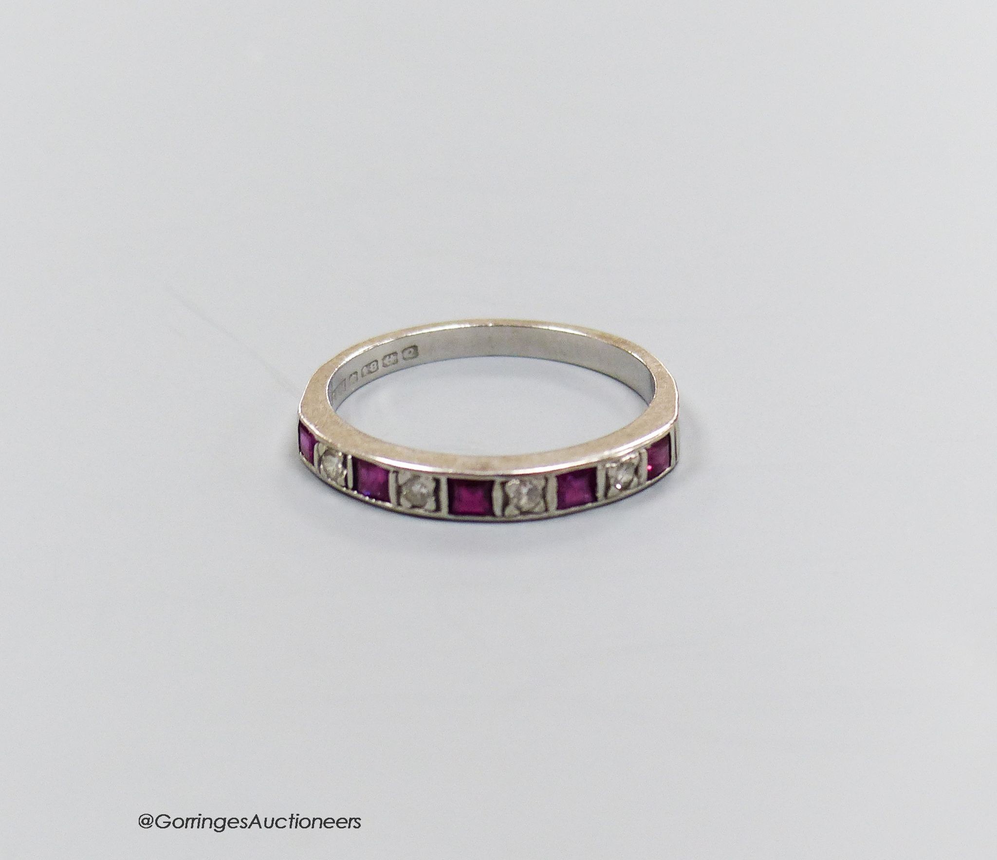 And 18 carat white gold ruby and diamond half eternity ring, size O, gross 2.7g.